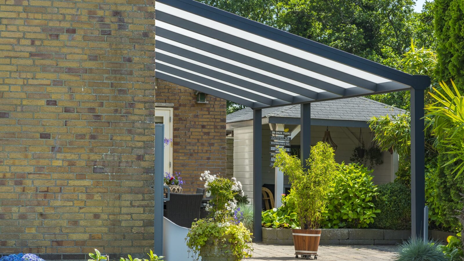 Polycarbonaat overkapping met aluminium frame tegen een bakstenen woning