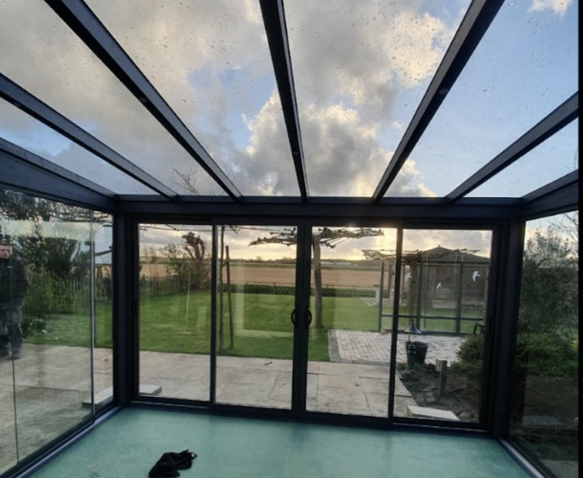 Glazen overkapping met glazen schuifwanden en glazen dak in een Nederlandse tuin